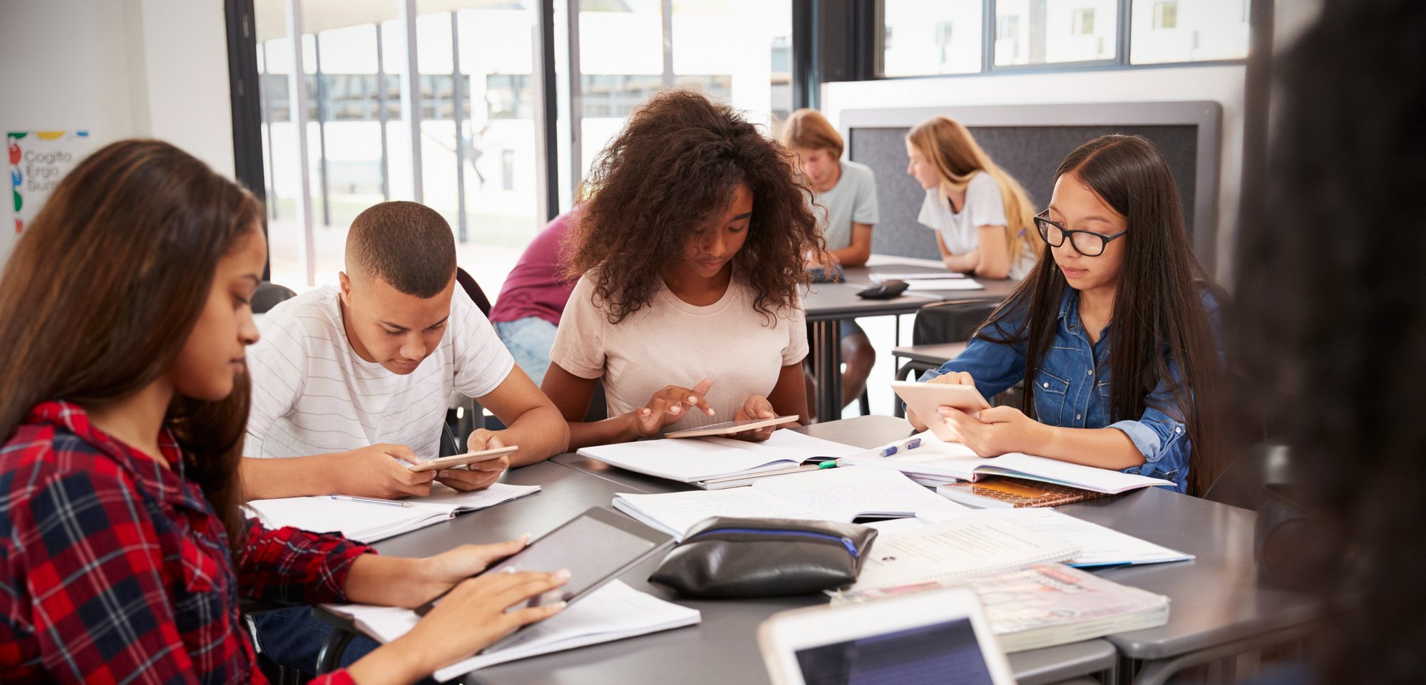 teacher-sitting-with-high-school-students-using-ta-2024-10-19-12-49-00-utc